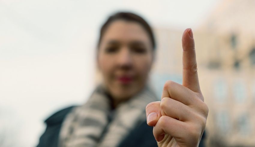 A woman is pointing with her finger in front of a building.