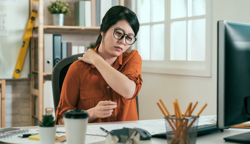 A woman is sitting at her desk with a pain in her neck.