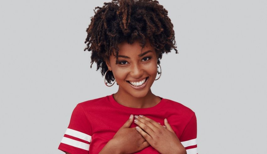 A young woman with dreadlocks posing with her hands on her chest.