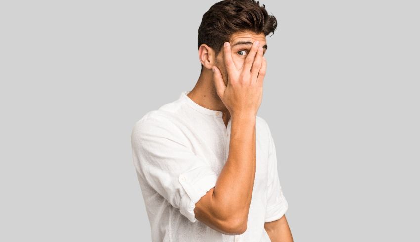 A young man covering his face with his hands.