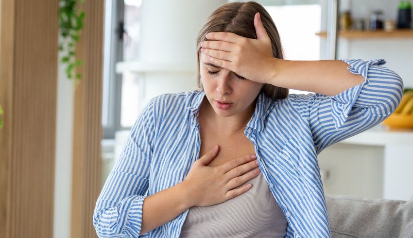 A woman is sitting on a couch with her hand on her chest.