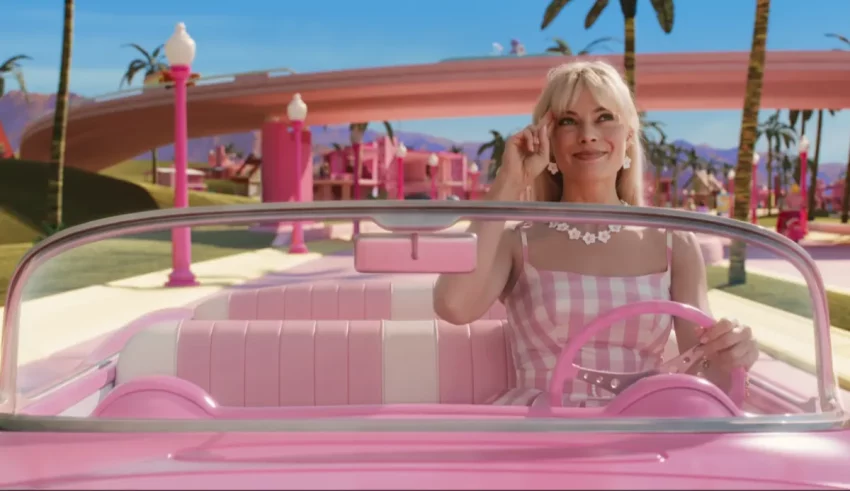A woman in a pink car driving down the road.