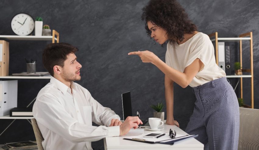 A woman is pointing at a man in the office.