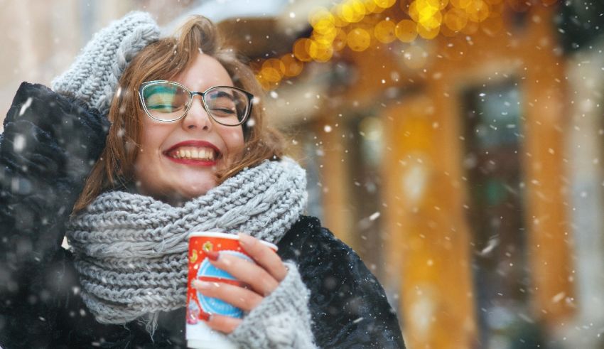 A woman is holding a cup of coffee in the snow.
