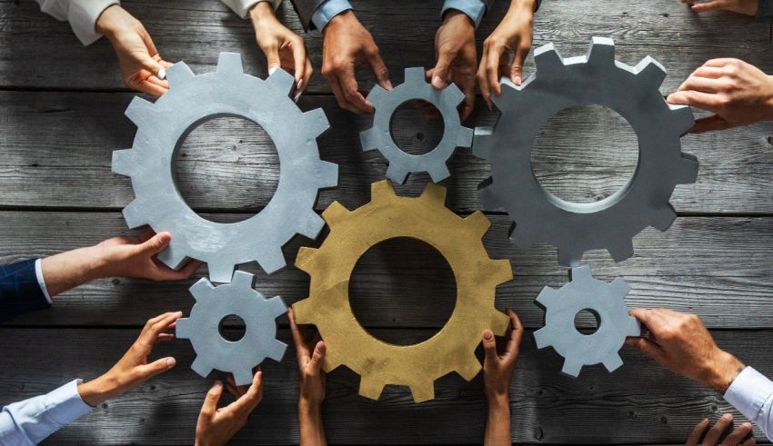 A group of business people holding gears on a wooden table.