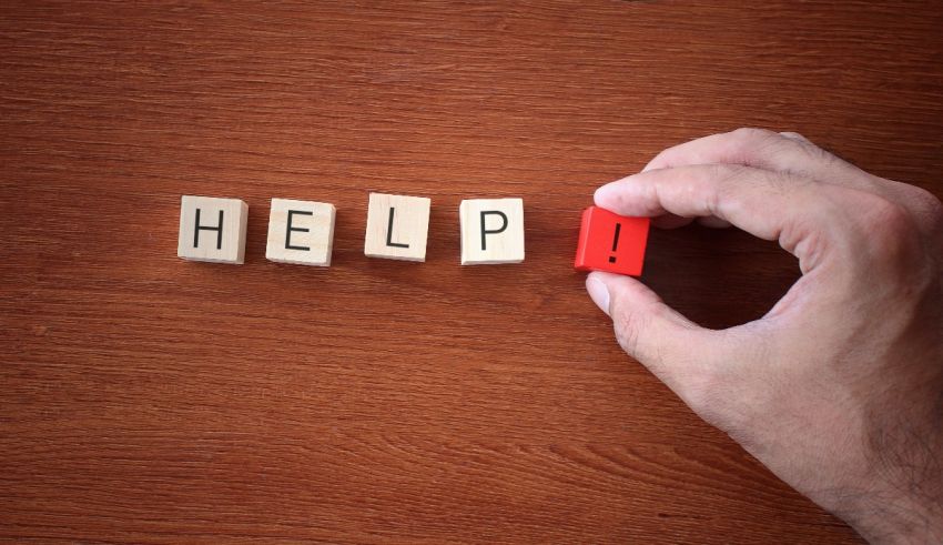 A hand holding a wooden block with the word help on it.