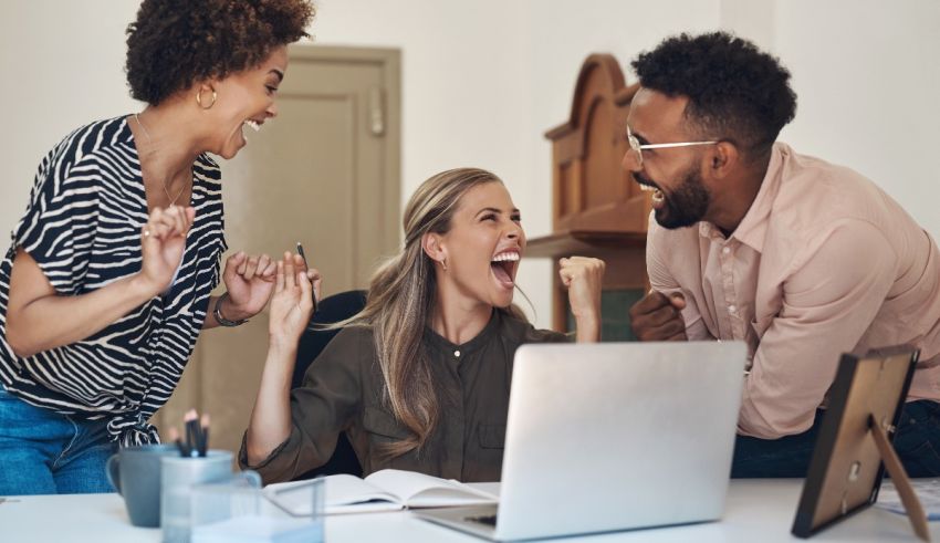 A group of people laughing at a table in an office.