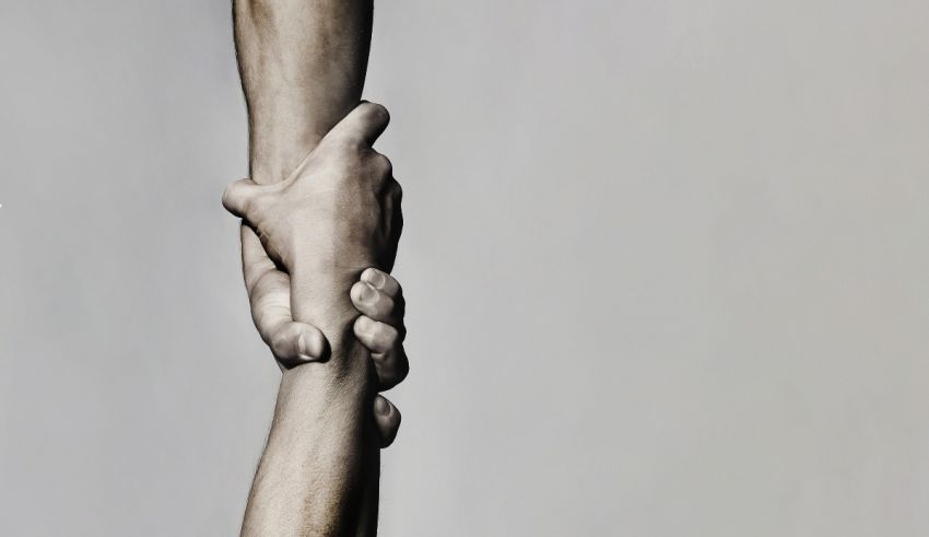 Two hands holding each other on a gray background.