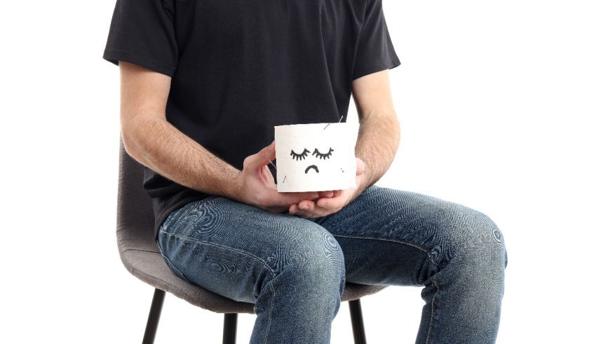 A man sitting on a chair holding a cup with a sad face on it.