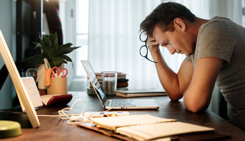 A man is sitting at a desk with a laptop in front of him.