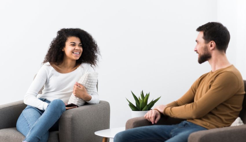 A man and woman sitting in chairs talking to each other.