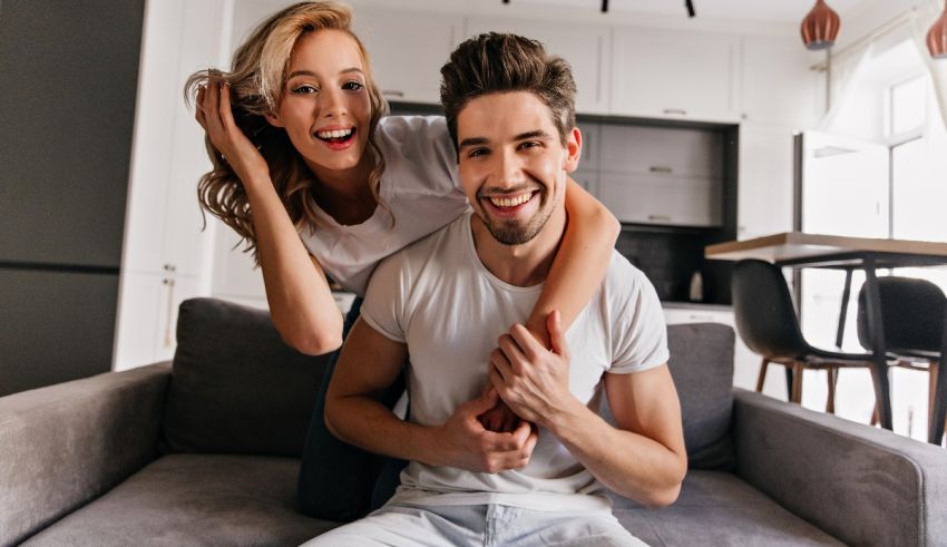 A young man and woman are sitting on a couch in their home.