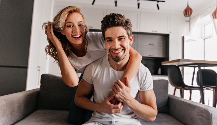 A young couple is sitting on a couch in their home.