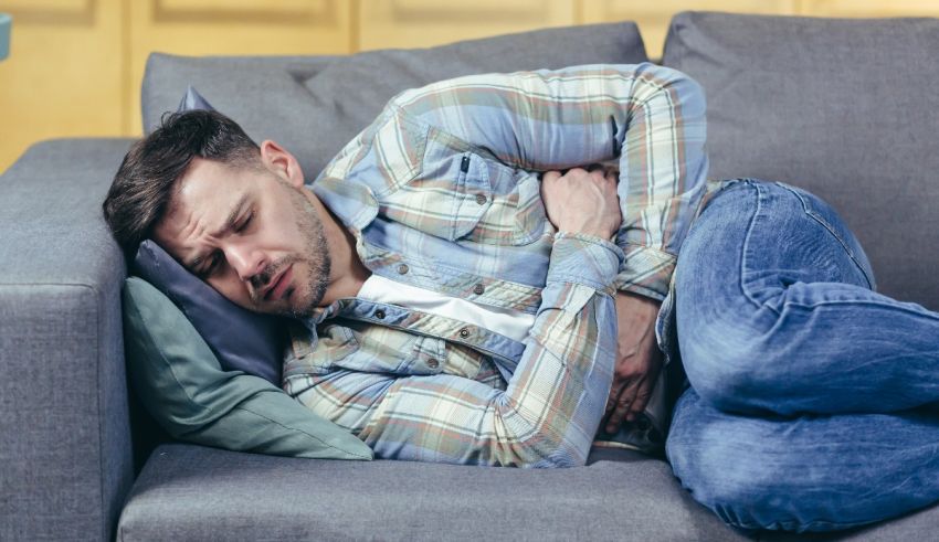 A man is lying on a couch with his hands on his stomach.