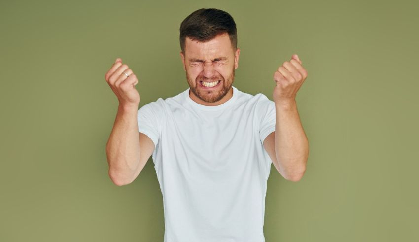 A man with his fists up on a green background.