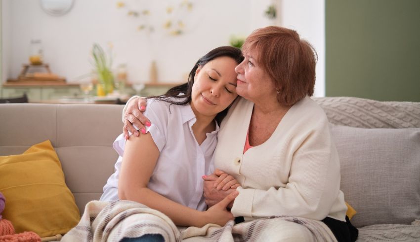 A woman is hugging her mother on the couch.