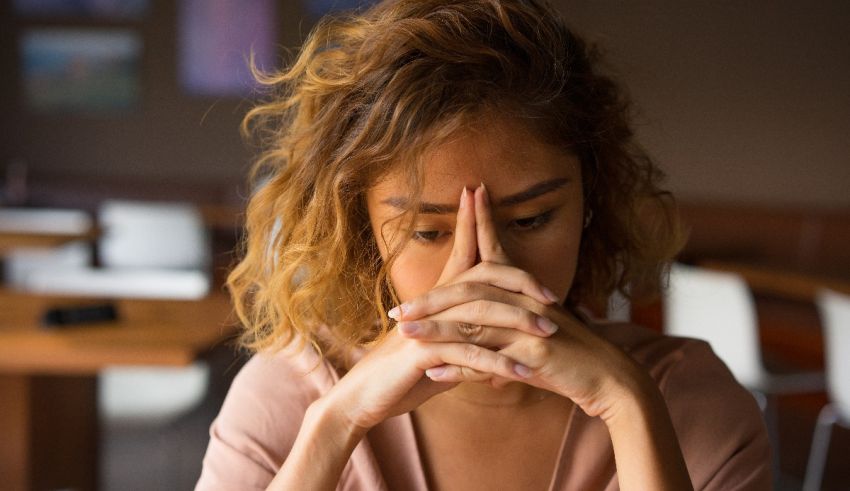 A woman is sitting at a table with her hands on her face.