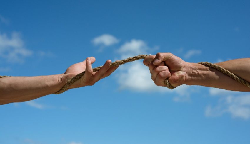 Two hands holding a rope against a blue sky.