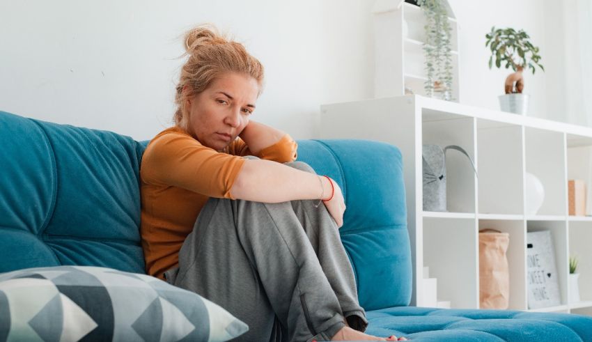 A woman sitting on a blue couch in her home.