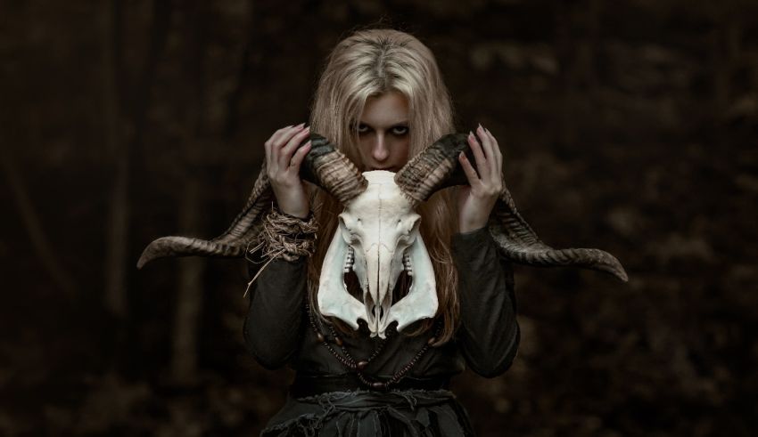 A woman with long horns holding a ram skull.