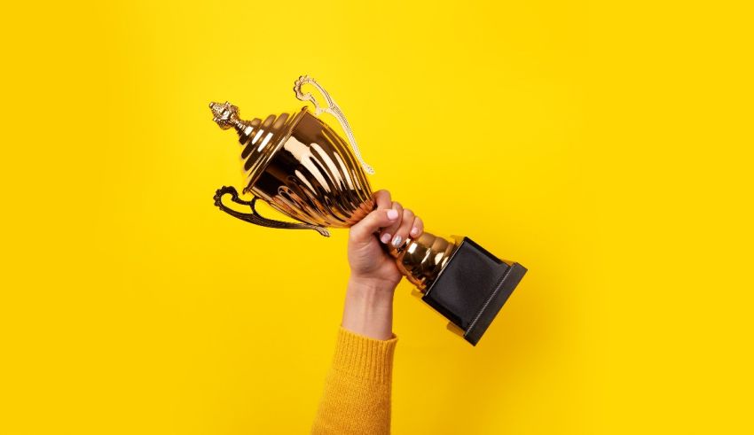 A woman holding a gold trophy on a yellow background.