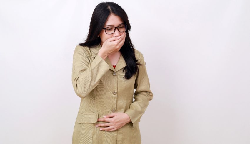 A woman in a tan coat covering her mouth with her hand.