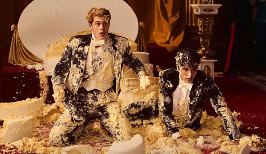 Two men in tuxedos sitting on top of a pile of cake.