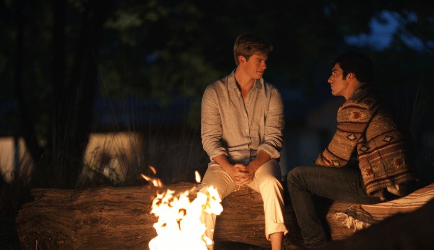 Two men sitting around a campfire at night.