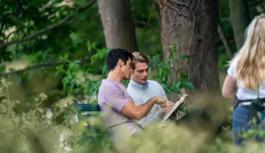 Two people sitting on a bench reading a book.