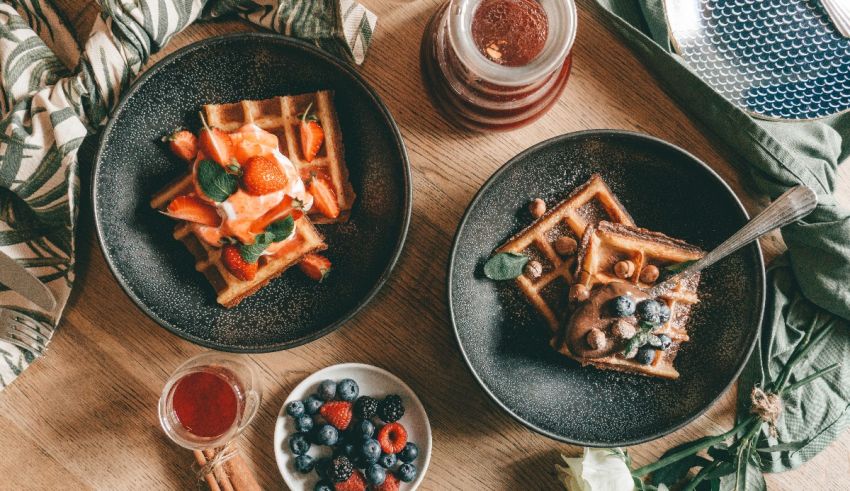 Two plates with waffles and berries on a wooden table.