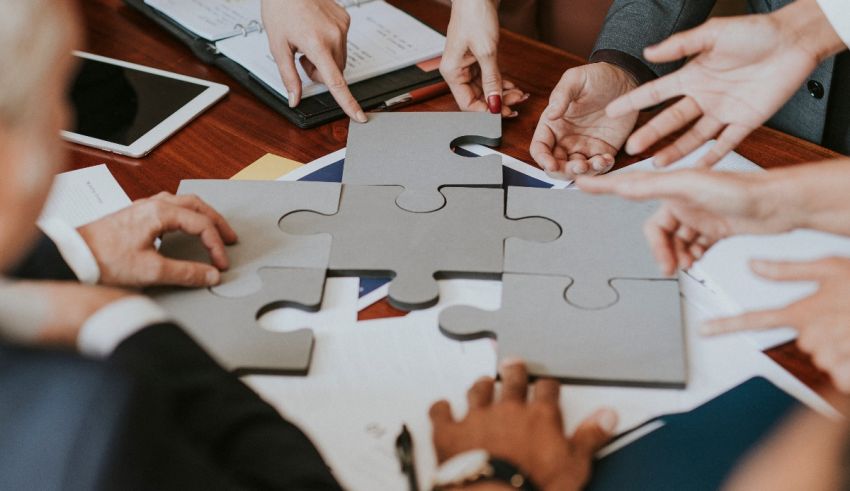 A group of business people putting puzzle pieces together on a table.