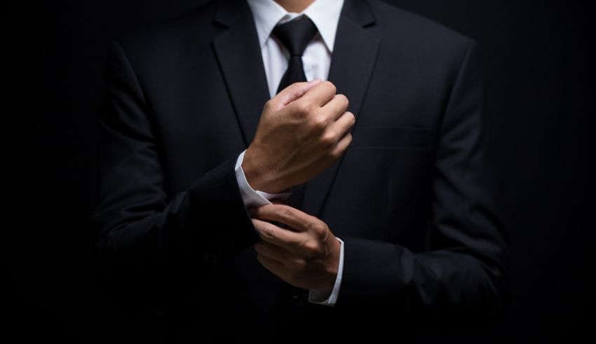 A man in a suit is adjusting his tie.