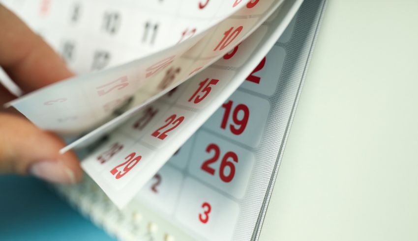 A person is holding a calendar on a desk.