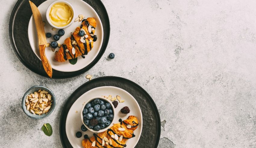 Two plates of food with blueberries and almonds on them.