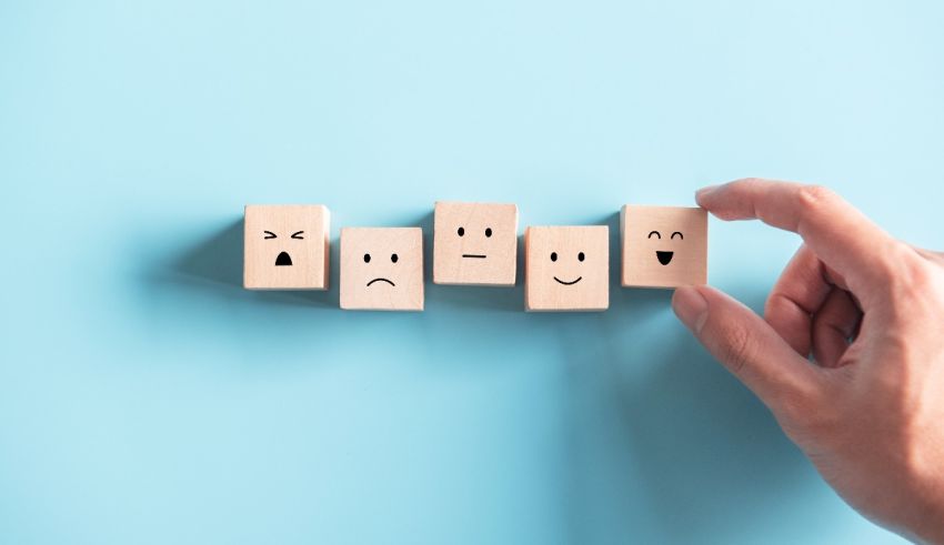 A hand is holding a set of wooden cubes with emoticons on them.