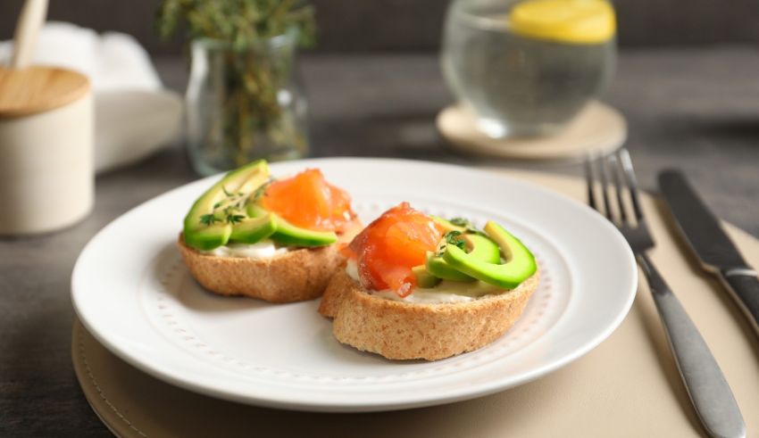 Two toasts with salmon and avocado on a plate.