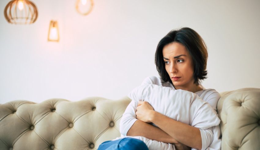 A woman sitting on a couch with a pillow under her arm.