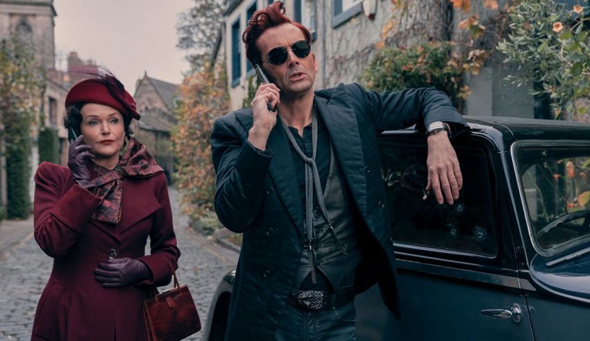 A man and woman standing next to a car on a cobblestone street.