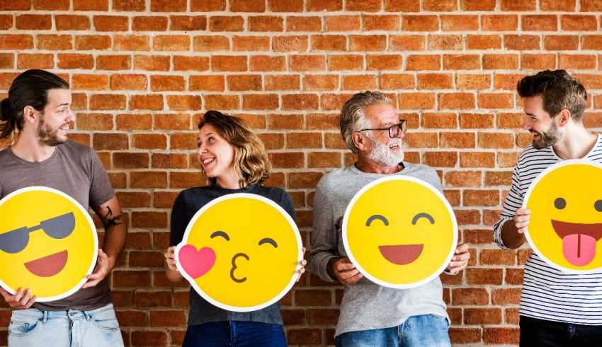 A group of people holding emoji signs in front of a brick wall.