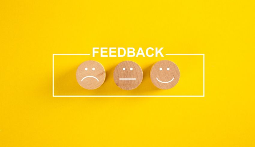 Three wooden smiley faces with the word feedback on a yellow background.