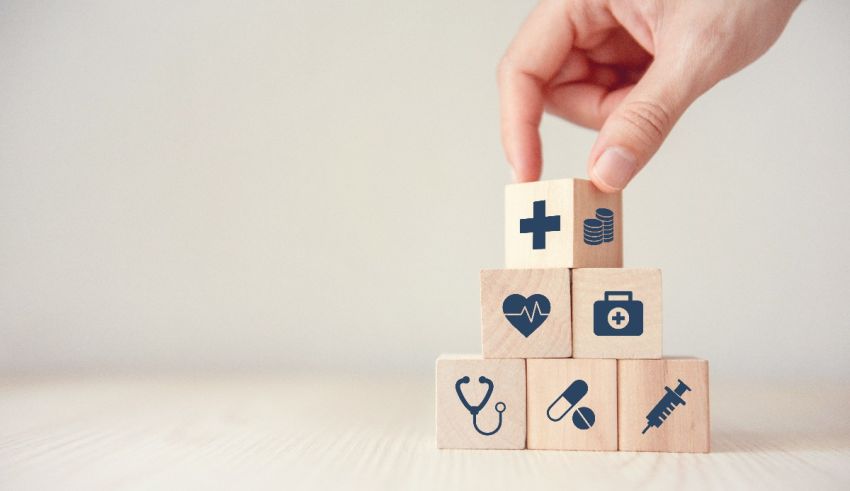 A hand is holding wooden blocks with medical icons on them.