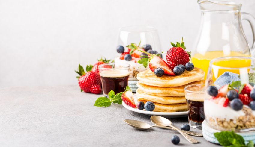 Pancakes with fruit and juice on a table.