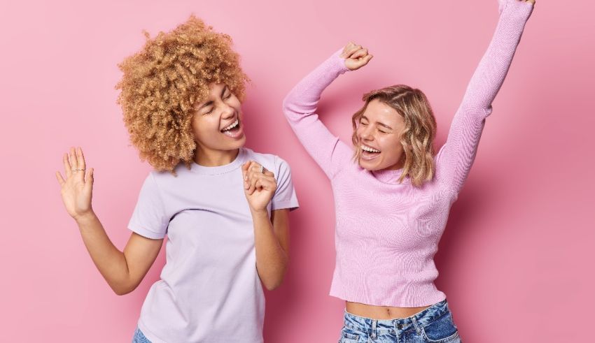 Two young women celebrating on a pink background.