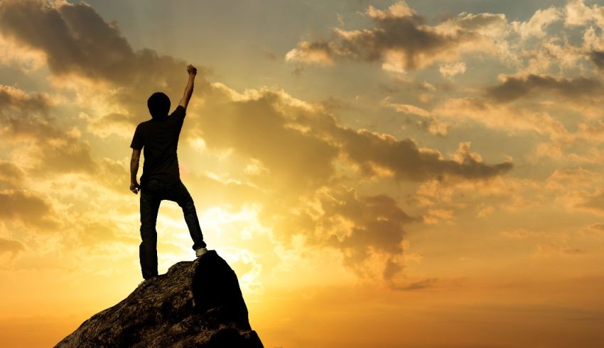 A man standing on top of a mountain with his arms raised.