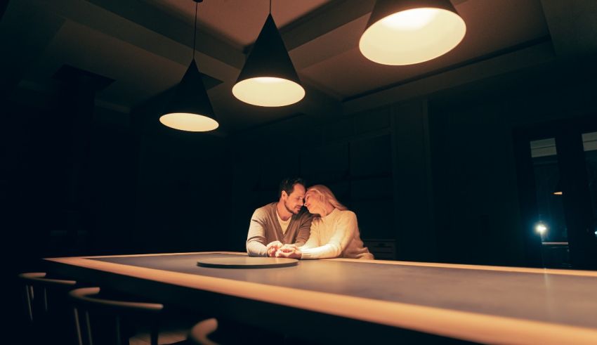 A couple embracing at a table in a dark room.