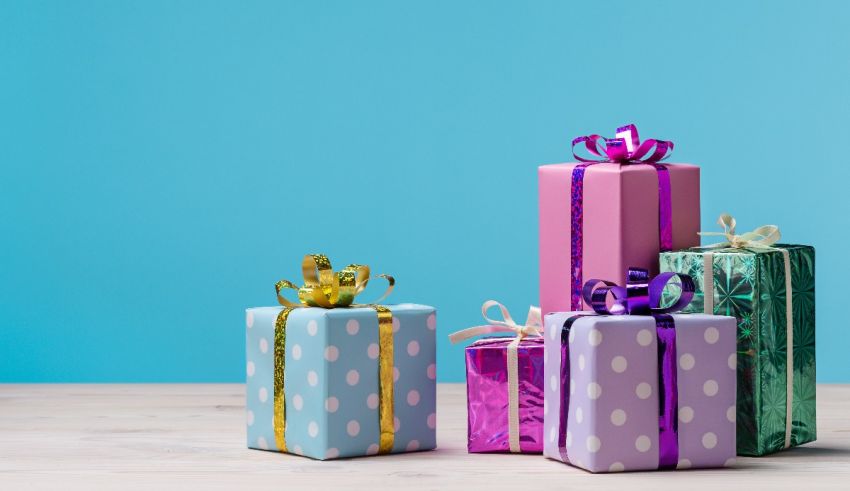 Colorful gift boxes on a wooden table against a blue background.