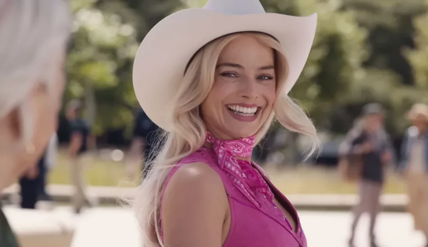 A woman in a pink cowboy hat is smiling.