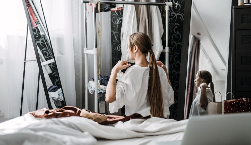 A woman is standing in front of a mirror in her bedroom.