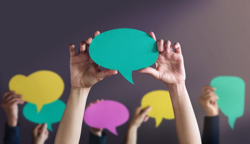 A group of people holding up colorful speech bubbles.