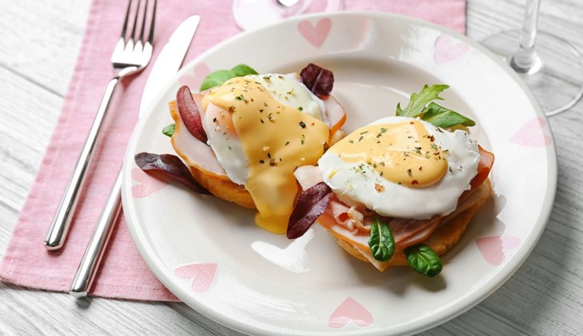 Two eggs benedict on a plate with a fork.